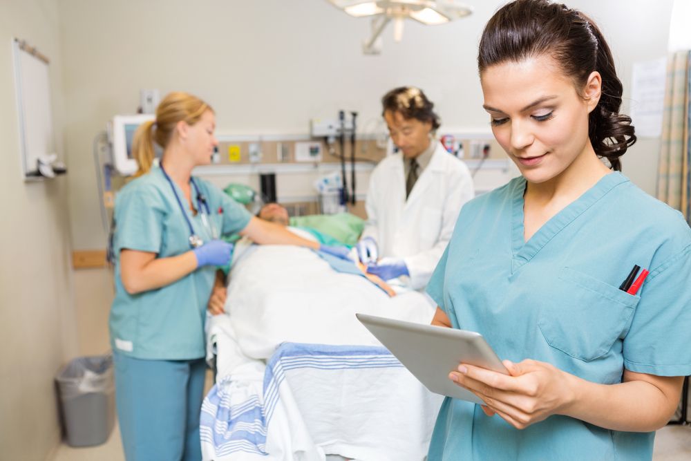 Nurse Using Digital Tablet While Doctor And Colleague Operating